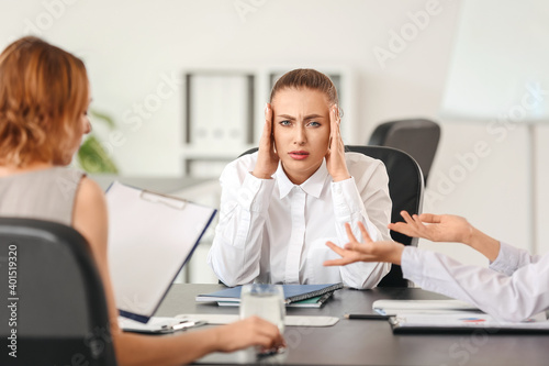 Fotografija Stressed woman with headache and noisy people in office
