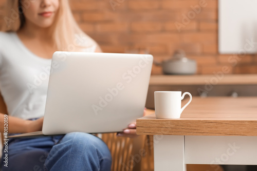 Beautiful young woman with laptop in kitchen