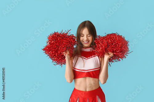 Beautiful young cheerleader on color background photo