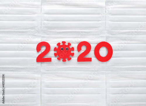 Red felt numbers 2020 on white respirators background. First zero in the form of a corona virus with googly eyes. Review of the year.