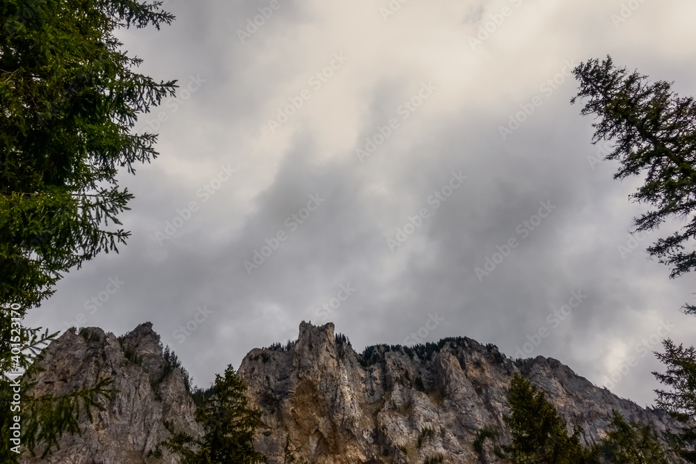 rugged mountains and trees with rainclouds at the sky
