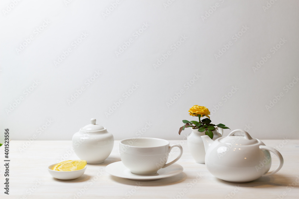 tea cup with saucer, teapot, sugar bowl, yellow rose in milk jug and lemon on white background ready for drinking tea cup with saucer, teapot, sugar bowl, yellow rose in milk jug and lemon on white background ready for drinking