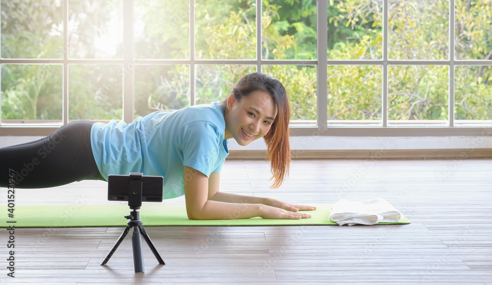 Young asian woman happy doing yoga and looking at smartphone from home. Light effect. Young asian woman happy doing yoga and looking at smartphone from home. Light effect.