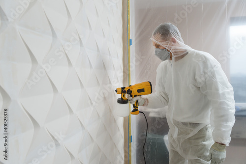 The painter is painting a 3d wall with a spray gun.