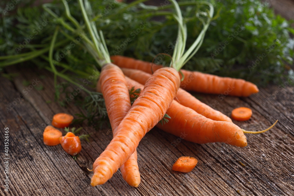 Fresh carrots with tops lying on a wooden table. Rustic. Carrots are a great element for vegans, keto and paleo diets. The concept of healthy eating. Fresh carrots with tops lying on a wooden table. Rustic. Carrots are a great element for vegans, keto and paleo diets. The concept of healthy eating.