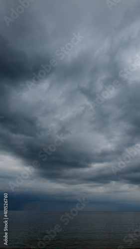 Moody dramatic dark contrasting clouds over calm sea. Storm approaching. 