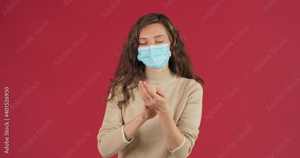 Portrait on red background masked woman protects health from infection with respiratory virus uses bottle with transparent alcohol antiseptic sanitizer to clean washing hand treatment from bacteria Portrait on red background masked woman protects health from infection with respiratory virus uses bottle with transparent alcohol antiseptic sanitizer to clean washing hand treatment from bacteria