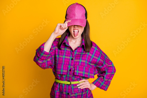 Photo of cool rock brown hair girl cover face tongue out wear pink headwear shirt isolated on bright yellow color background