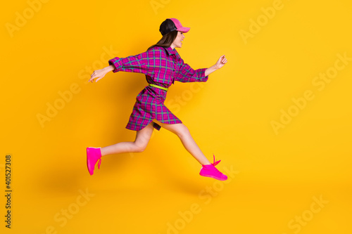 Full length profile portrait of attractive lady running headwear magenta outfit isolated on yellow color background