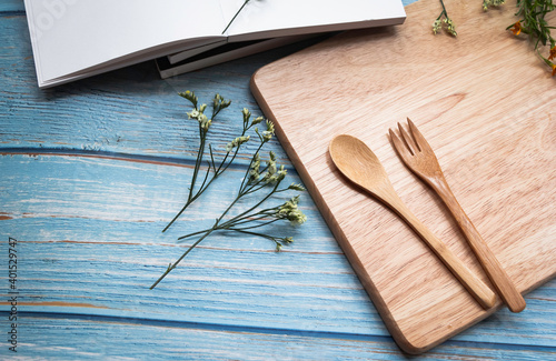 Wooden fork and spoon put  on timber board beside beautiful small flower