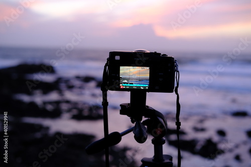 A camera taking picture of a sunset on the seaside.