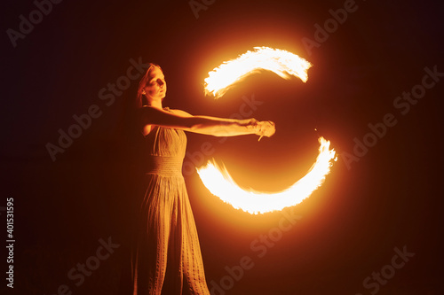 Photo with a long exposure. Fire show by woman in dress in night Carphatian mountains. Beautiful landscape