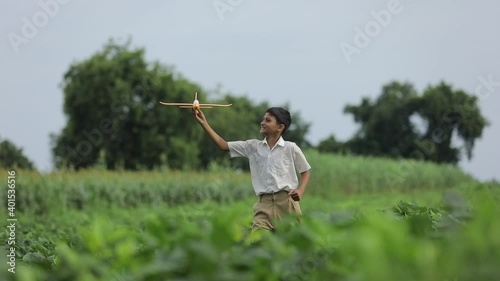 dreams of flight! indian child playing with toy airplane at green field