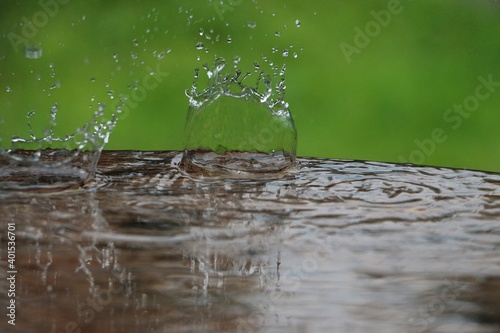 ranidrops are falling in a puddle on the wet table in the garden