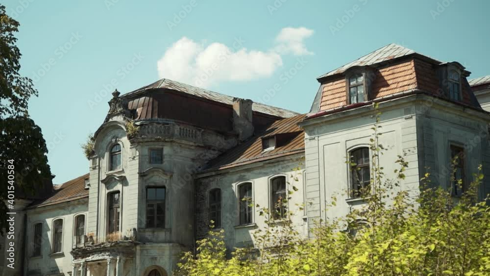 Zheludok, Belarus - August 17 2020: Beautiful old ancient abandoned manor palace with a roof overgrown with plants, a shabby facade, destroyed columns