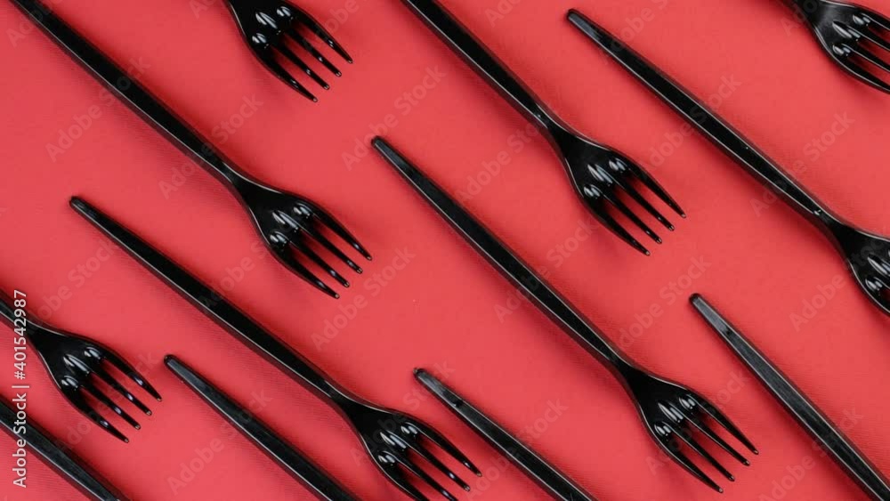 Eco concept. Plastic disposable forks stacked in rows on a red background rotate in a circle. Pattern Eco concept. Plastic disposable forks stacked in rows on a red background rotate in a circle. Pattern