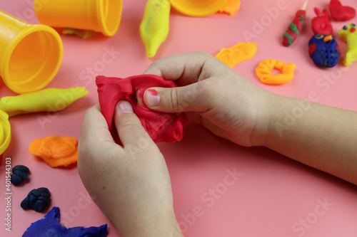 Child sculpts from colored plasticine on the table, hands close-up