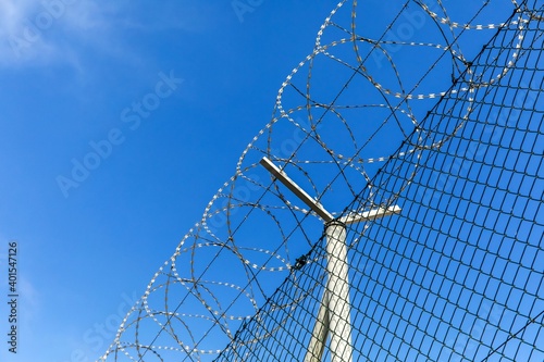 Barbed wire against a blue sky. Prison concept. Entry order. Military base. Detail of New Fence with Barbed Wire