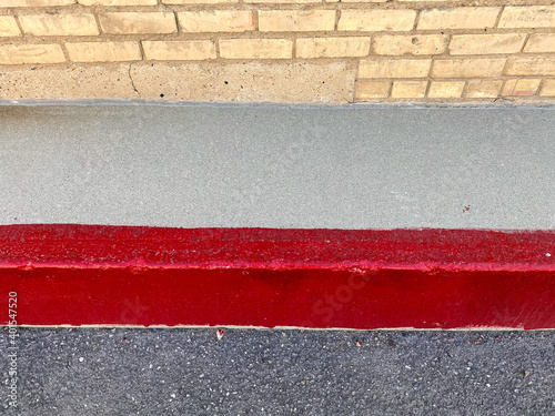 bright red strip painted on sidewalk showing pavement and edge of brick warehouse building 