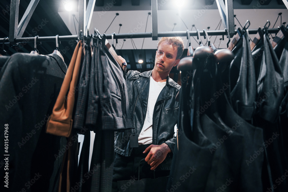 Weekend shopping. Young guy in modern store with new clothes. Elegant expensive wear for men