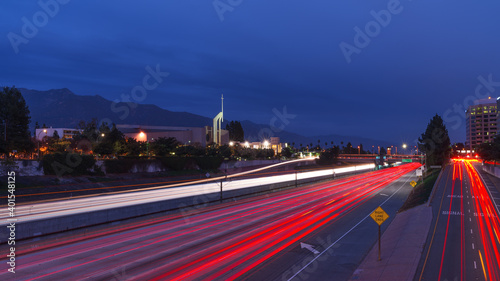 Traffic on the Foothill (210) Freeway in Pasadena, California creates bright red and white light trails in the foreground, with the Lake Metro Station and Lake Avenue Church visible in the distance.
