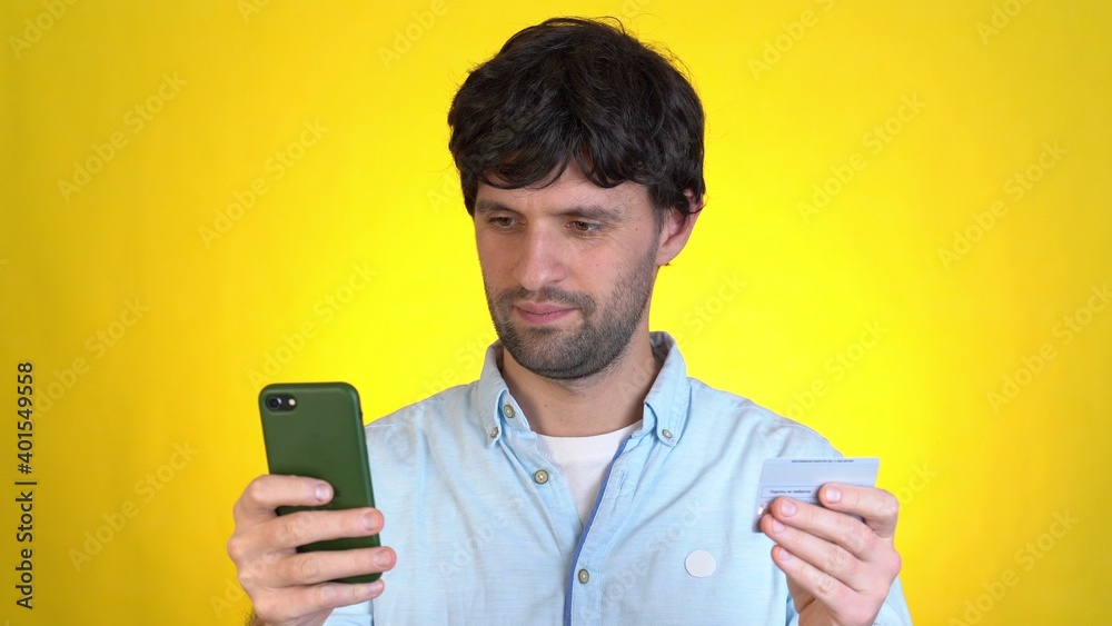 Happy man using hold in hand credit bank card mobile cell phone just found out great big win news isolated on yellow background studio People lifestyle concept Happy man using hold in hand credit bank card mobile cell phone just found out great big win news isolated on yellow background studio People lifestyle concept