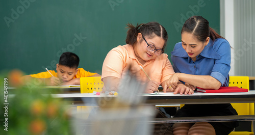 Asian Autism children with disability kid on wheelchair in special classroom with teacher.  photo