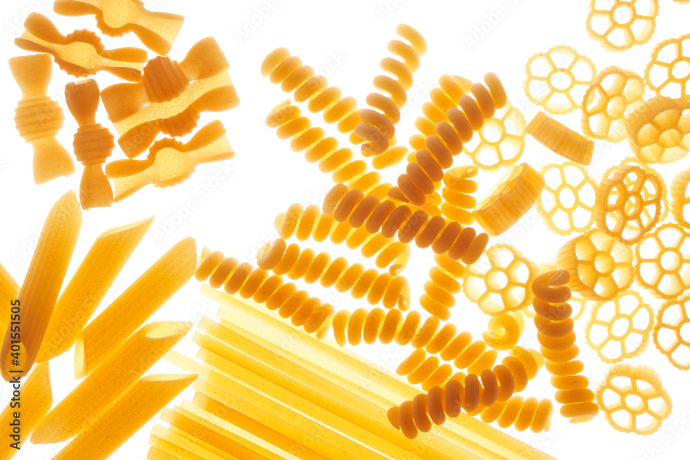 Mix of different varieties of pasta on white background, bottom lighting, assorted macaroni.