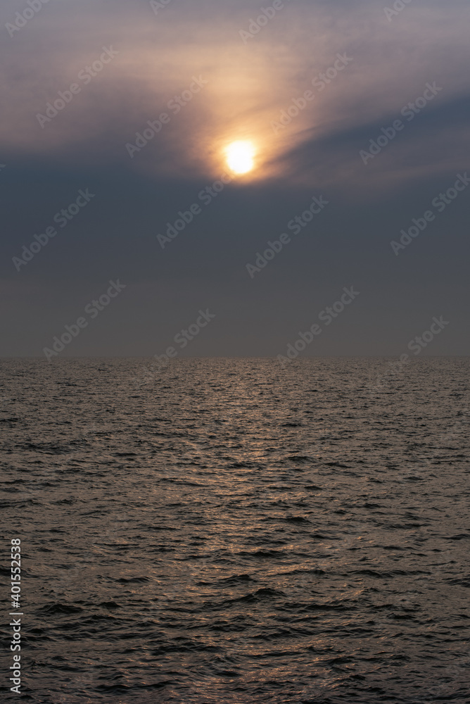 Fototapeta premium sun behind clouds or fog in the sea