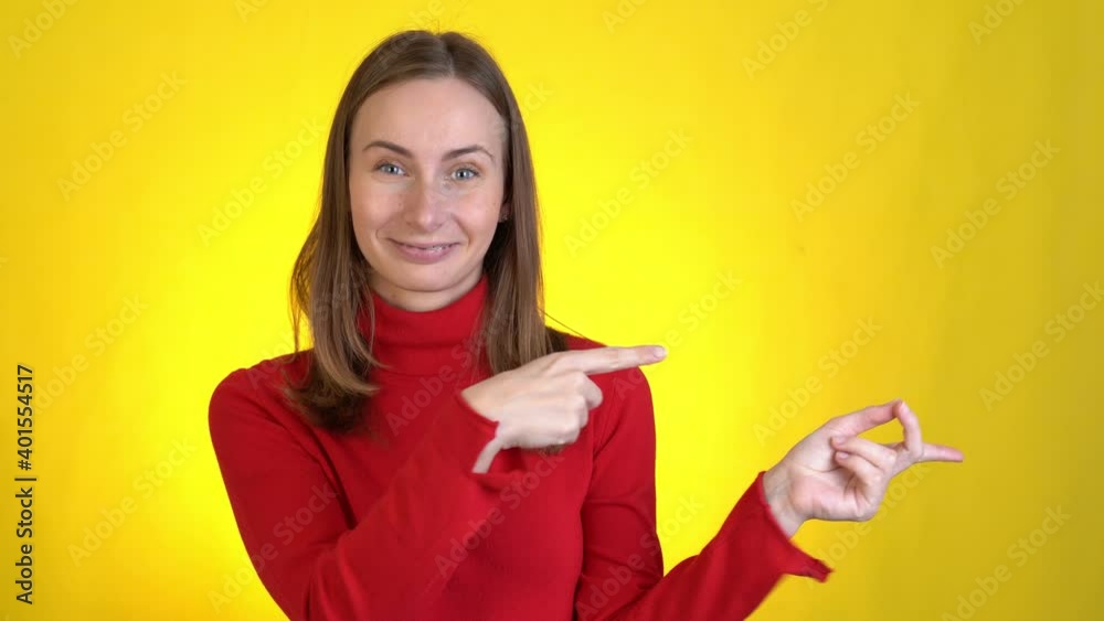 Smiling excited woman posing isolated on yellow background studio. People lifestyle concept. Pointing index fingers hands aside camera doing winner gesture Smiling excited woman posing isolated on yellow background studio. People lifestyle concept. Pointing index fingers hands aside camera doing winner gesture