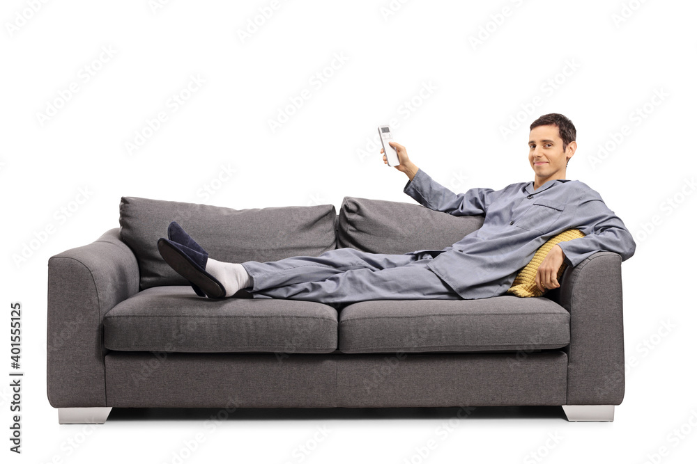 Man in pajamas laying on a sofa and holding a remote control from an air conditioning