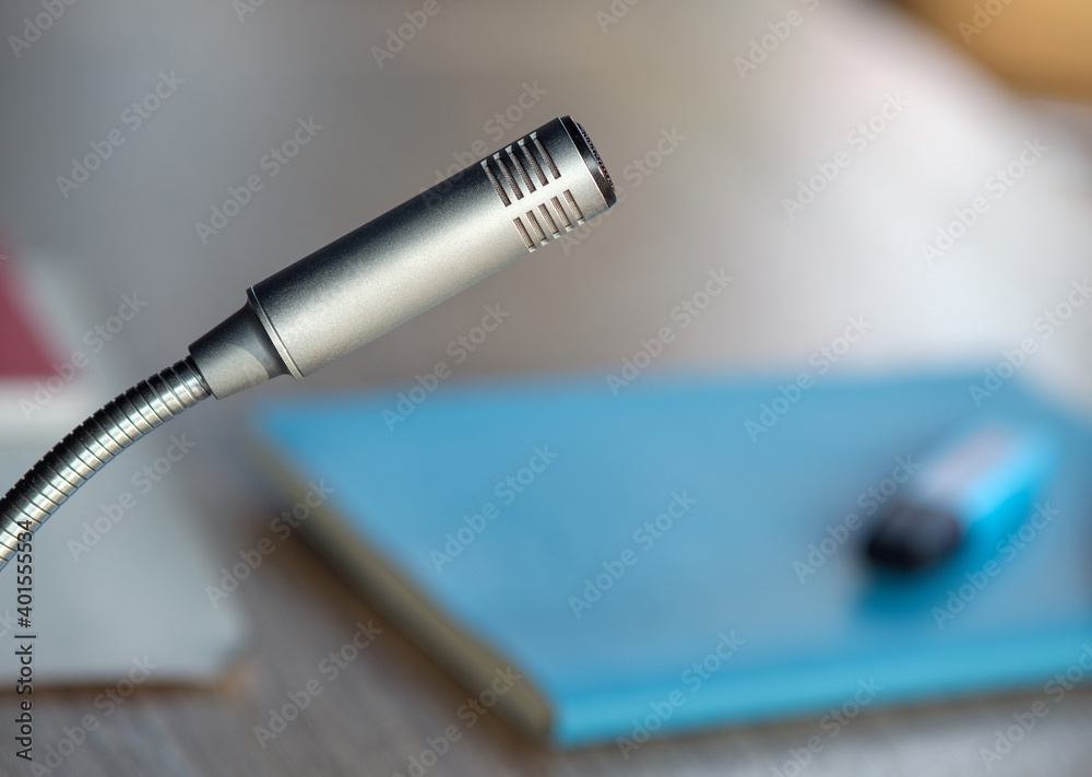 Extreme Nahaufnahme eines isolierten Mikrofons, seitlich von oben aufgenommen, mit Notizbuch und Stift im verschwommenen Hintergrund – selektiver Fokus viel Copyspace Extreme Nahaufnahme eines isolierten Mikrofons, seitlich von oben aufgenommen, mit Notizbuch und Stift im verschwommenen Hintergrund – selektiver Fokus viel Copyspace