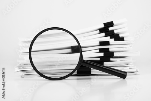 Stack of report paper documents with magnifying glass. Concept of business and search. photo