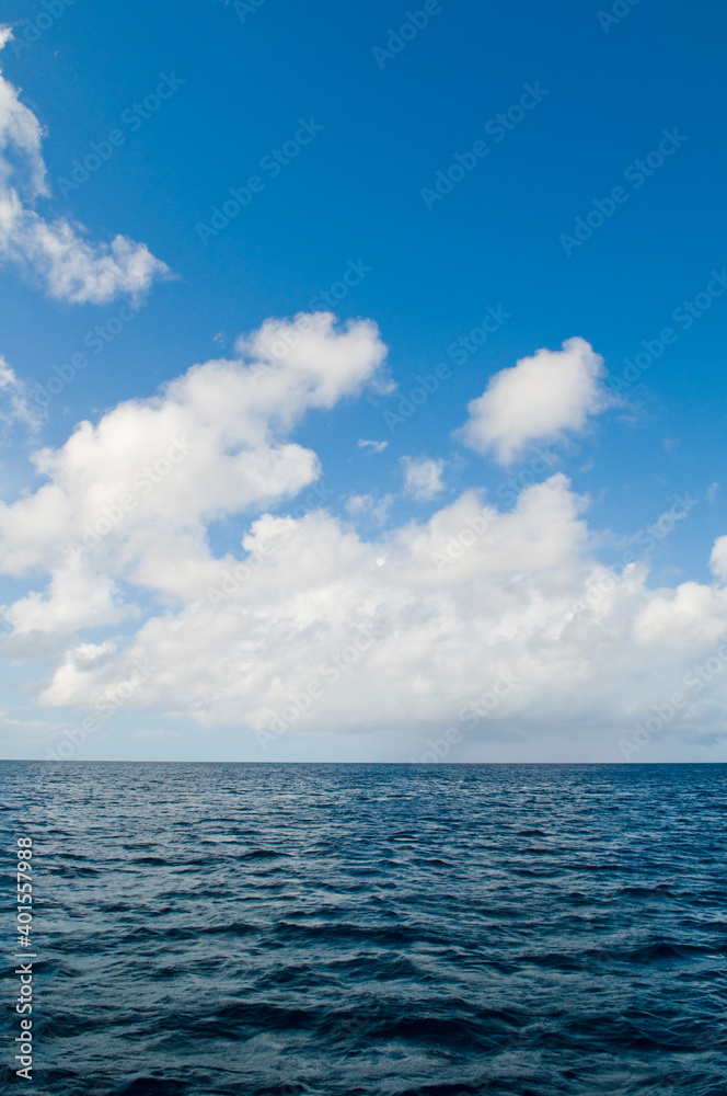 Deep ocean view with waves and white clouds. Relaxing seascape, endless sea, tropical waters background. Blue seas and skies separated by a far away horizon. Caribbean lifestyle themes