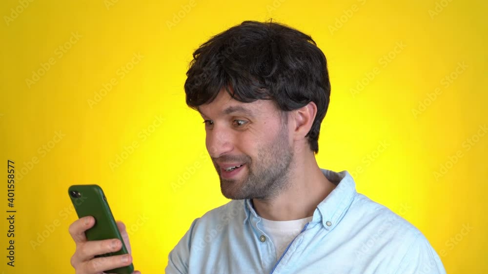 Surprised man isolated on yellow background studio. Using mobile cell phone hold fan of cash money in dollar banknotes Surprised man isolated on yellow background studio. Using mobile cell phone hold fan of cash money in dollar banknotes