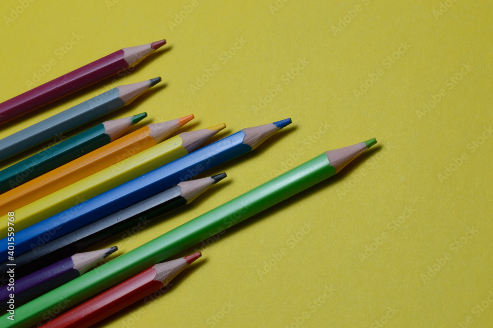 Fototapeta premium several multi-colored pencils lie on the yellow surface.