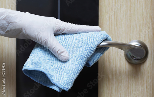 
Cleaning the room, a woman wipes the doorknob for added protection against coronavirus infection. Additional protection measures indoors.