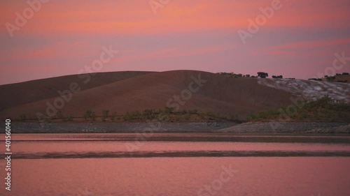 Desert like hill landscape with reflection on the water on a dam lake reservoir at sunset in Terena, Portugal photo