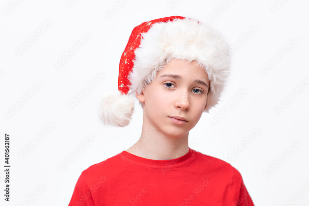 portrait of a boy in a hat of Santa Claus on a white background, a teenager in a red cap with white fur and a tassel, New Year's discounts and Christmas sale portrait of a boy in a hat of Santa Claus on a white background, a teenager in a red cap with white fur and a tassel, New Year's discounts and Christmas sale