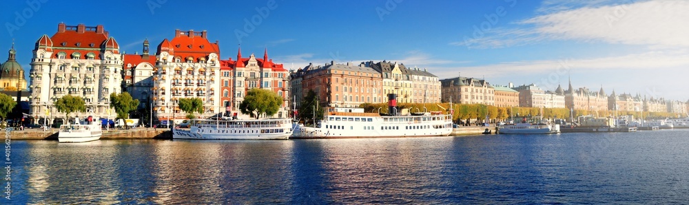 Passenger ships moored to a pier in a city centre of Stockholm, Sweden. Golden trees, clear blue sky. Panoramic autumn cityscape. Traveling, national landmarks, sightseeing theme - obrazy, fototapety, plakaty 