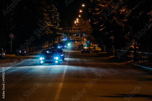 Cars drive through the winter night city. Light from lanterns and headlights.