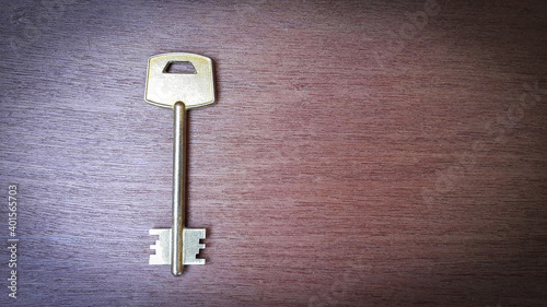 Large shiny vintage metal key on old wooden background