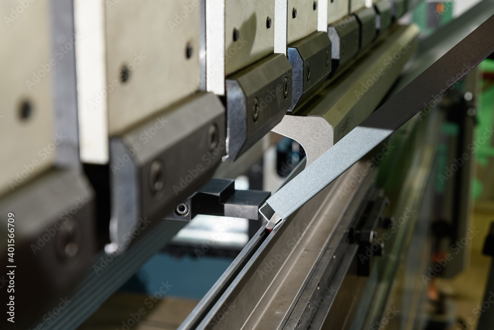 worker operating metal press machine at workshop.