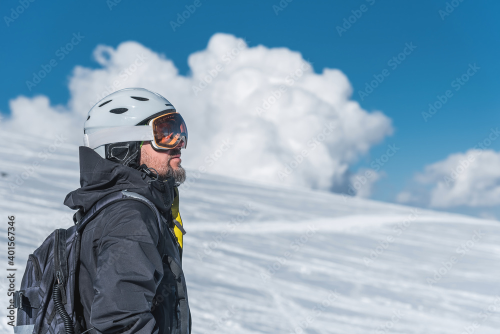 A man with skis stands high in the mountains enjoying the scenery. Go downhill skiing, extreme relaxation