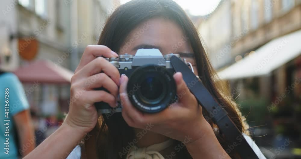 Close up portrait of cheerful beautiful female in good mood with camera standing outdoors in city. Happy pretty young Asian woman tourist taking photo. Photographer taking pictures. Urban concept Close up portrait of cheerful beautiful female in good mood with camera standing outdoors in city. Happy pretty young Asian woman tourist taking photo. Photographer taking pictures. Urban concept