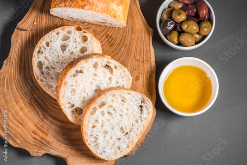 Traditional Italian ciabatta with olives and olive oil on a wooden board on the table. Craft bread and healthy food concept