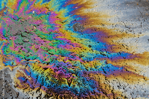 Colored oil stain on the asphalt. A rainbow slick of gasoline. Abstract background.