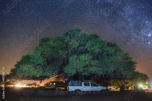 Night view of Toyota Hilux with Roof top tent under the Acacia tree (Camel Thorn) and the starry sky. Stars over Sesriem camping site, Namibia. photo