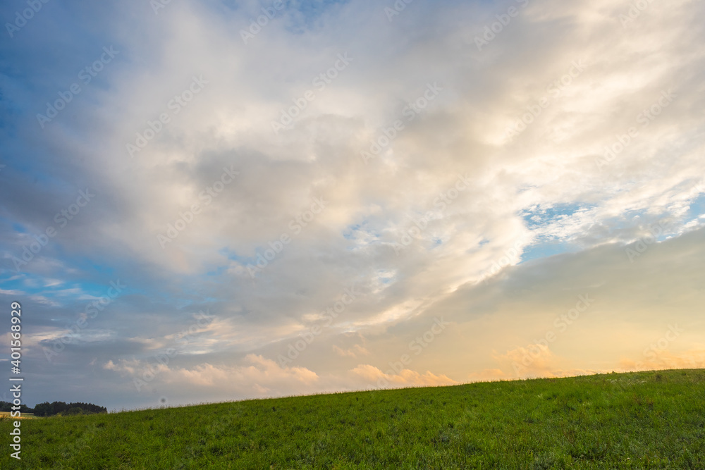Green field with agriculture meadow and blue sky. Panoramic view to grass on the hill on sunny spring day