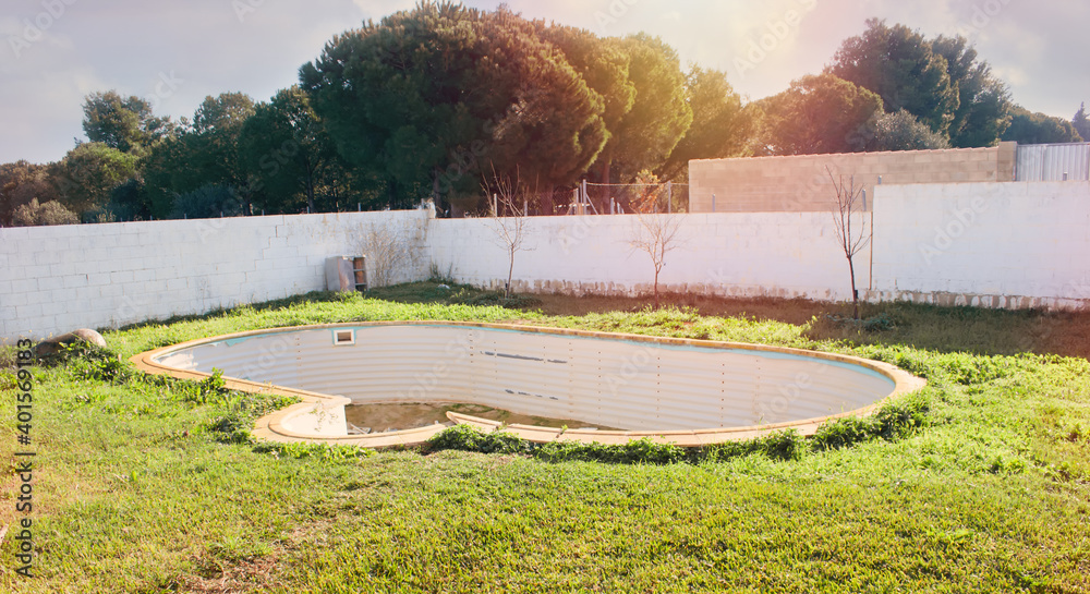 Fototapeta premium Old abandoned swimming pool overgrown with grass in the village